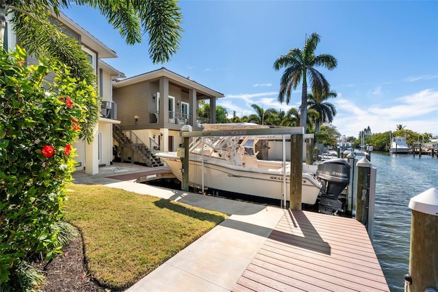 view of dock with a water view, boat lift, stairs, and a yard