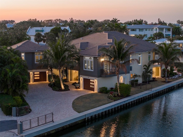 view of front of home featuring central AC unit, a balcony, a water view, an attached garage, and decorative driveway