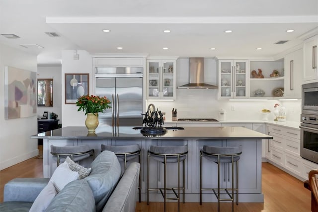 1610 S Lake Shore Dr, Sarasota, FL 34231 - kitchen featuring a kitchen island, wall chimney range hood, built in appliances, a kitchen bar, and a sink