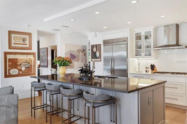 1610 S Lake Shore Dr, Sarasota, FL 34231 - kitchen with a kitchen island, a sink, light wood-style floors, appliances with stainless steel finishes, and wall chimney range hood