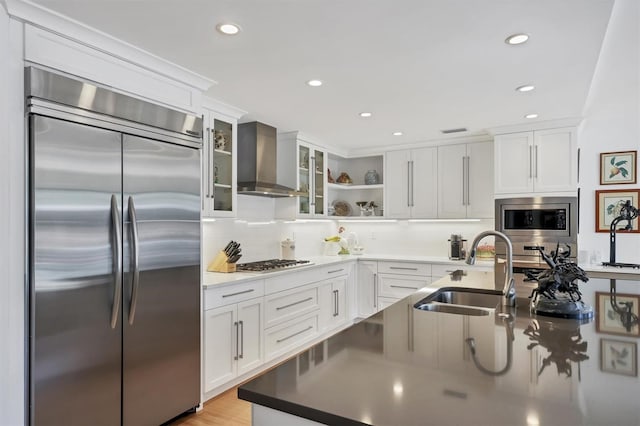 1610 S Lake Shore Dr, Sarasota, FL 34231 - kitchen featuring built in appliances, white cabinetry, wall chimney exhaust hood, and a sink