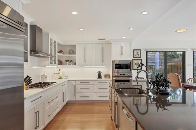 1610 S Lake Shore Dr, Sarasota, FL 34231 - kitchen featuring light wood-type flooring, a sink, wall chimney range hood, glass insert cabinets, and built in appliances