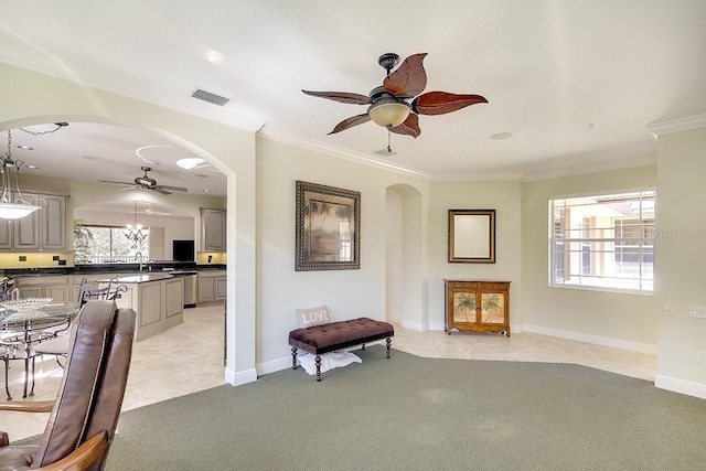 living area with a ceiling fan, arched walkways, visible vents, and light carpet