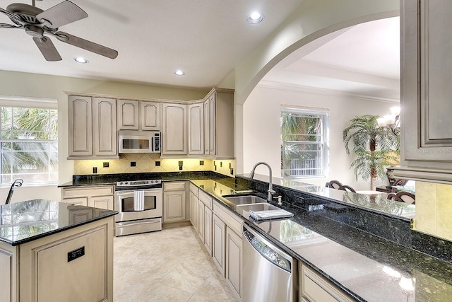 kitchen featuring stainless steel appliances, a wealth of natural light, a sink, and decorative backsplash