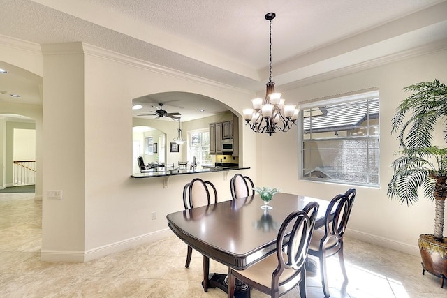 dining room with arched walkways, a tray ceiling, a textured ceiling, and baseboards