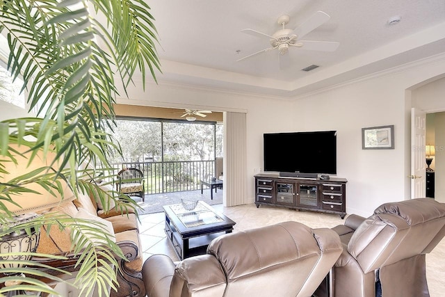 tiled living area featuring a ceiling fan, a tray ceiling, visible vents, and crown molding