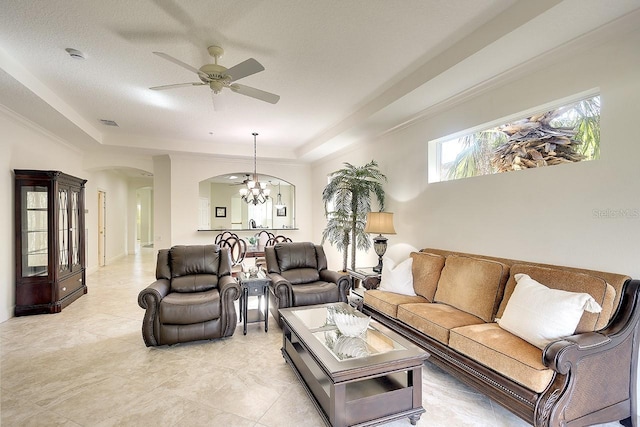 living area with visible vents, arched walkways, a tray ceiling, and ceiling fan with notable chandelier