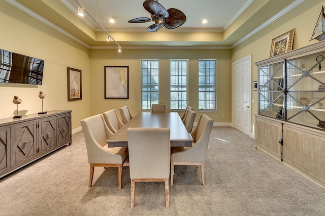 dining room featuring ornamental molding, a raised ceiling, light colored carpet, and baseboards