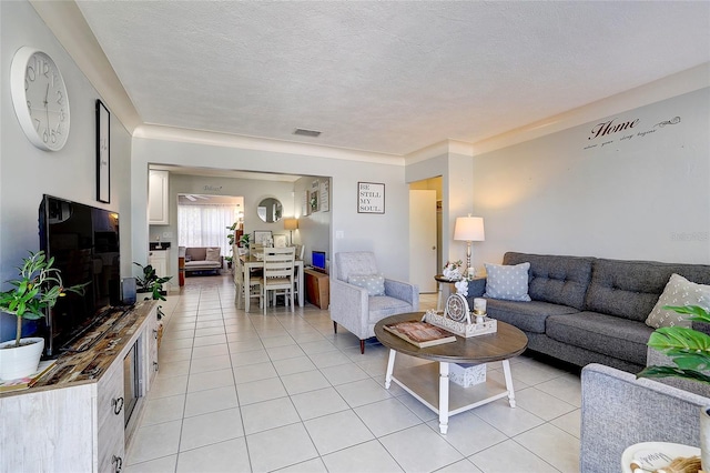 living area featuring light tile patterned floors, a textured ceiling, and visible vents