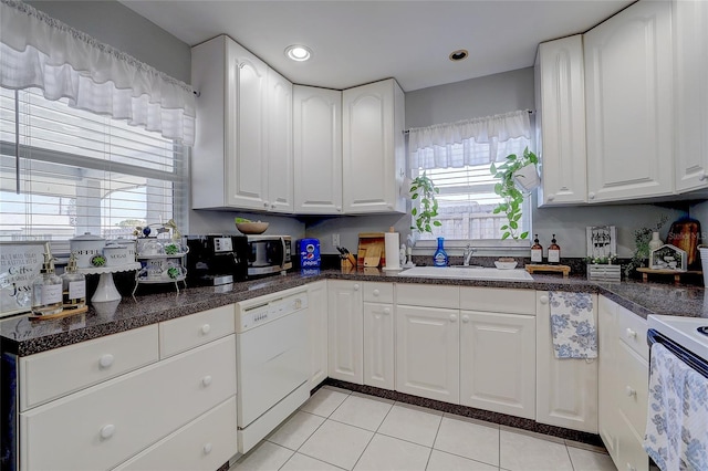 kitchen with a sink, dark countertops, white appliances, and light tile patterned flooring