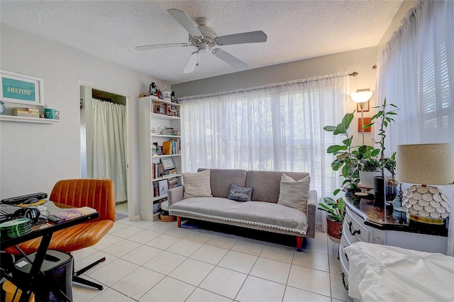 living room featuring a ceiling fan, a textured ceiling, and light tile patterned floors