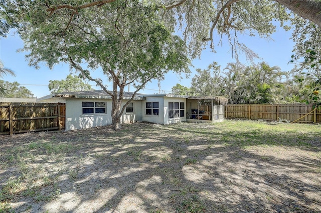 back of house with a sunroom, a fenced backyard, and stucco siding