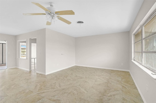 spare room featuring baseboards, visible vents, and ceiling fan