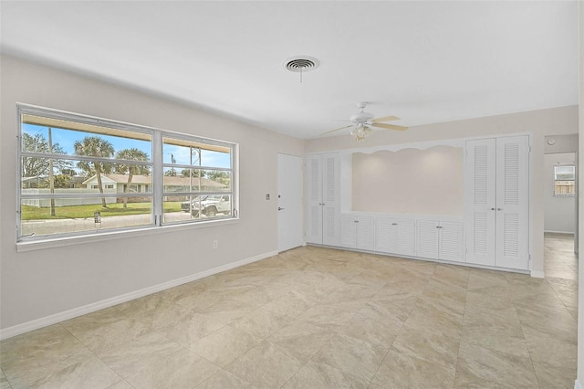 unfurnished room with ceiling fan, visible vents, and baseboards