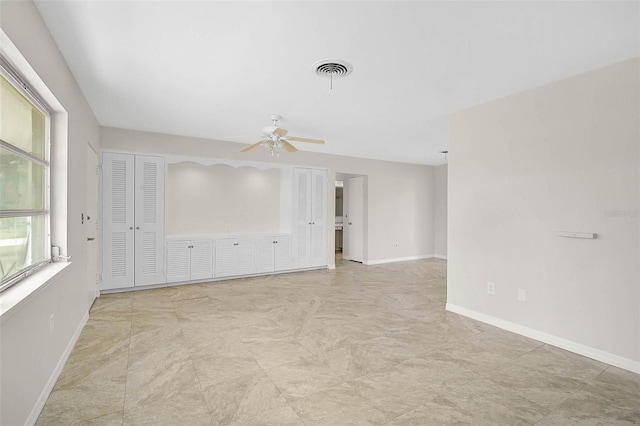 spare room featuring ceiling fan, visible vents, and baseboards