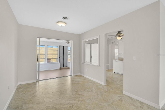 spare room with ceiling fan, visible vents, and baseboards