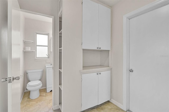 bathroom featuring toilet and baseboards