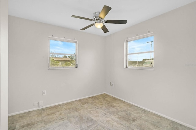 empty room with a ceiling fan, a wealth of natural light, and baseboards