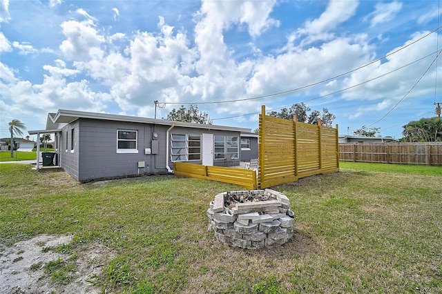 back of house with a fire pit, a yard, and fence