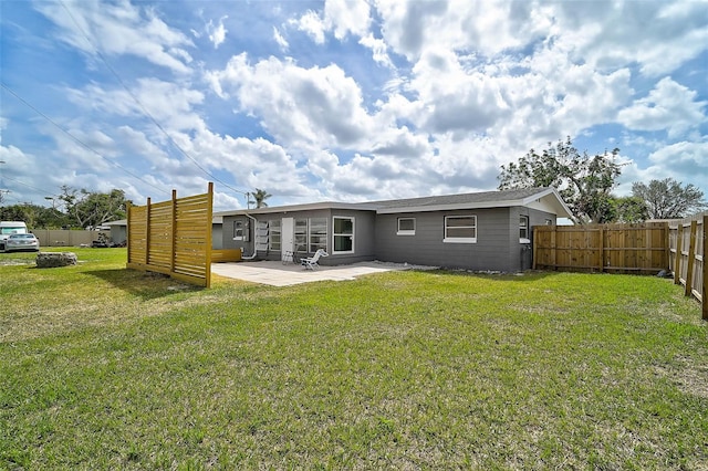 rear view of house with a patio, a lawn, and fence