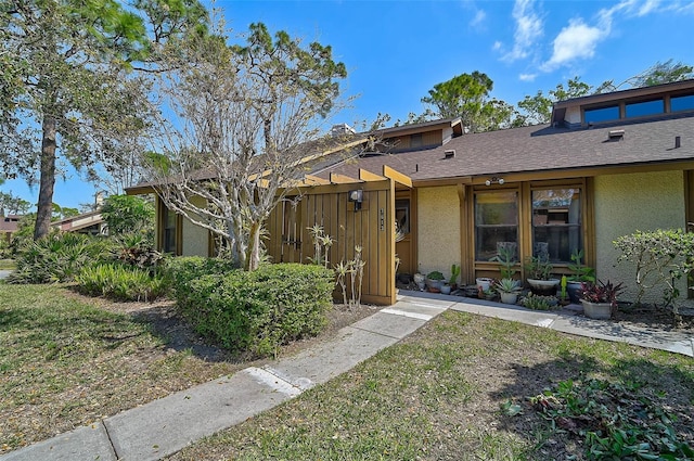 mid-century inspired home with roof with shingles and stucco siding