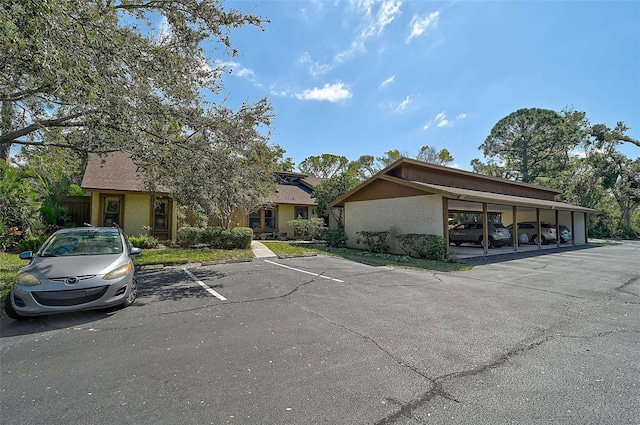 exterior space with covered and uncovered parking and stucco siding