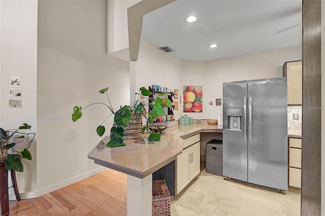 kitchen with light countertops, visible vents, stainless steel fridge, a peninsula, and baseboards