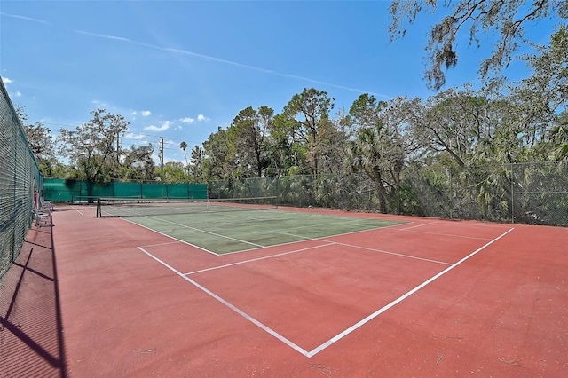 view of tennis court featuring community basketball court and fence