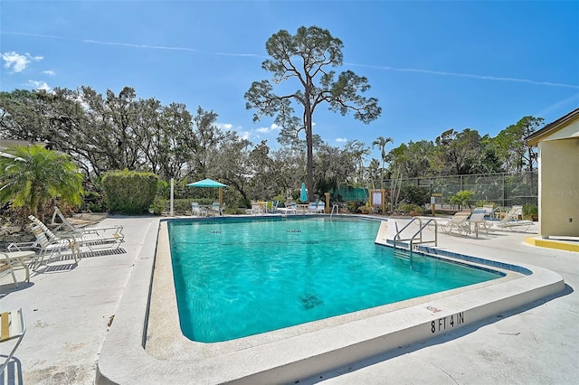 community pool with a patio and fence