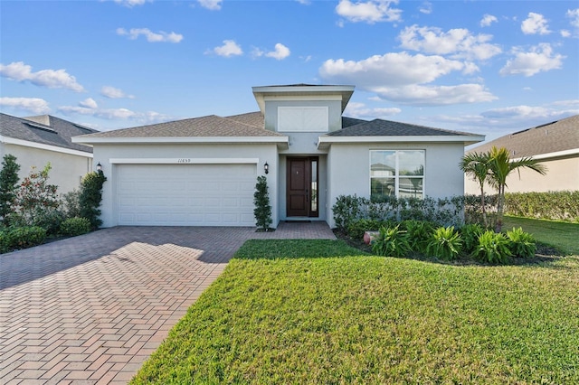 prairie-style house with decorative driveway, an attached garage, stucco siding, and a front yard