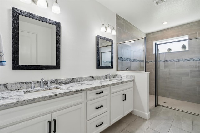 bathroom featuring visible vents, a sink, a shower stall, and double vanity