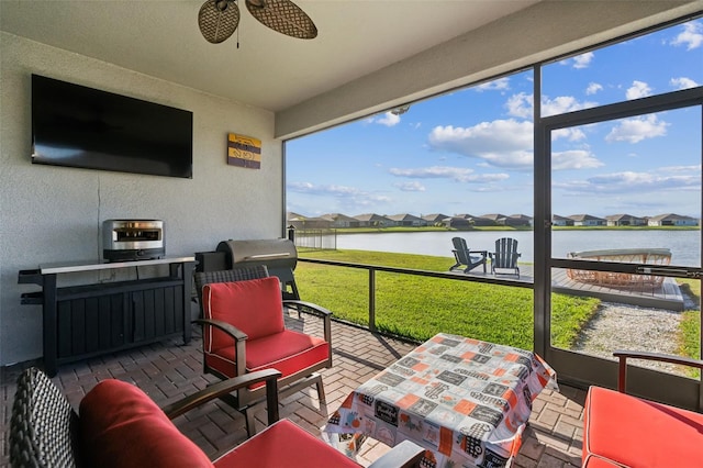 sunroom / solarium with a water view and ceiling fan