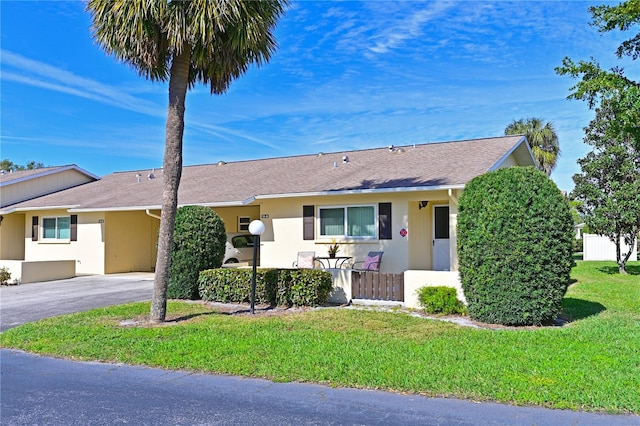 ranch-style house with a front yard, aphalt driveway, and stucco siding