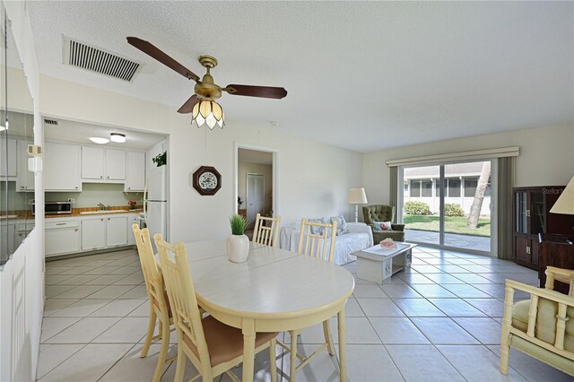 dining space with ceiling fan, visible vents, a textured ceiling, and light tile patterned flooring