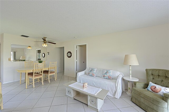 living room featuring light tile patterned floors, a textured ceiling, visible vents, and a ceiling fan