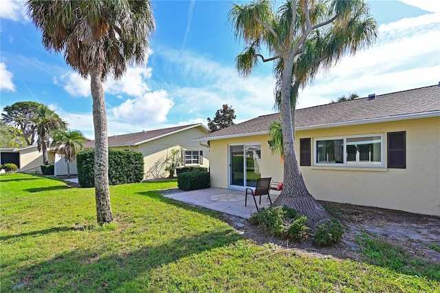 rear view of house featuring a patio, a lawn, and stucco siding