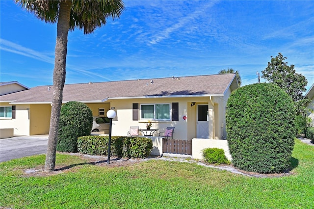 single story home with aphalt driveway, a front yard, and stucco siding