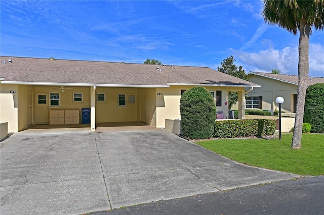 ranch-style home with concrete driveway, roof with shingles, a front lawn, and stucco siding