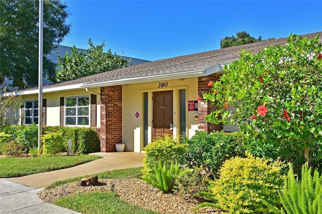 view of front of house with stucco siding, roof with shingles, and brick siding