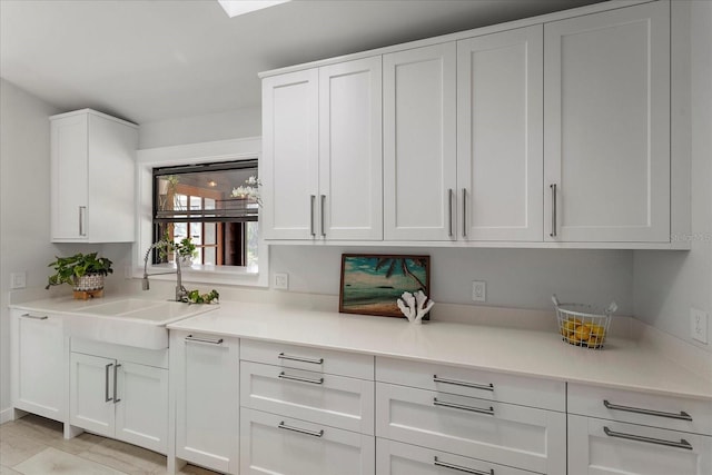 interior space with white cabinetry, light countertops, and a sink