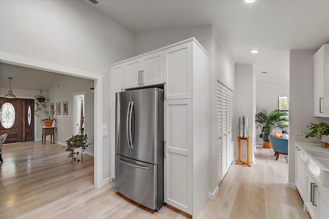 kitchen featuring baseboards, white cabinetry, light wood-style flooring, and freestanding refrigerator