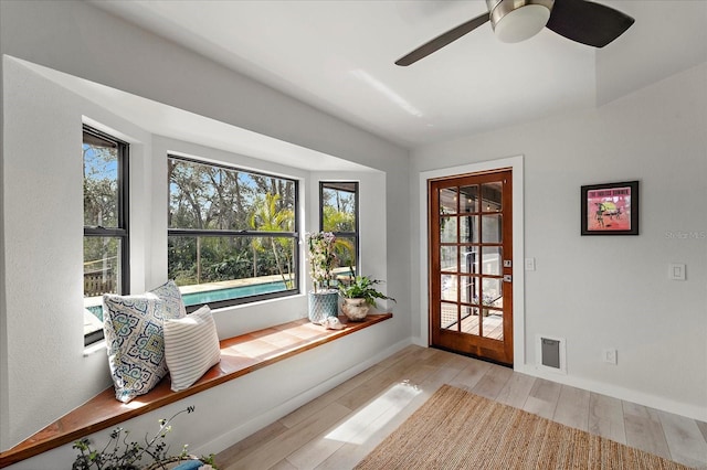 interior space with visible vents, a ceiling fan, baseboards, and wood finished floors