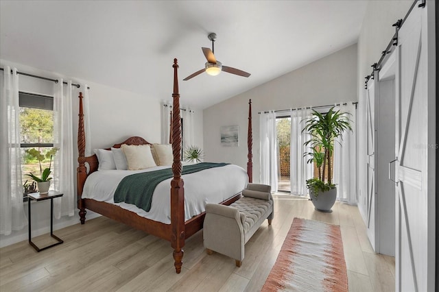 bedroom featuring access to exterior, lofted ceiling, a barn door, light wood-style floors, and a ceiling fan