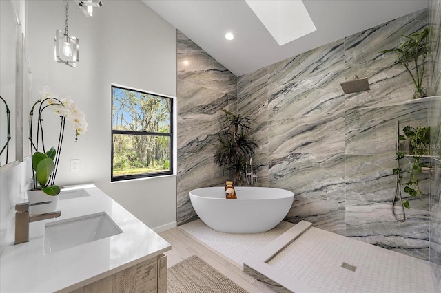 bathroom featuring a soaking tub, vaulted ceiling with skylight, a sink, walk in shower, and tile walls