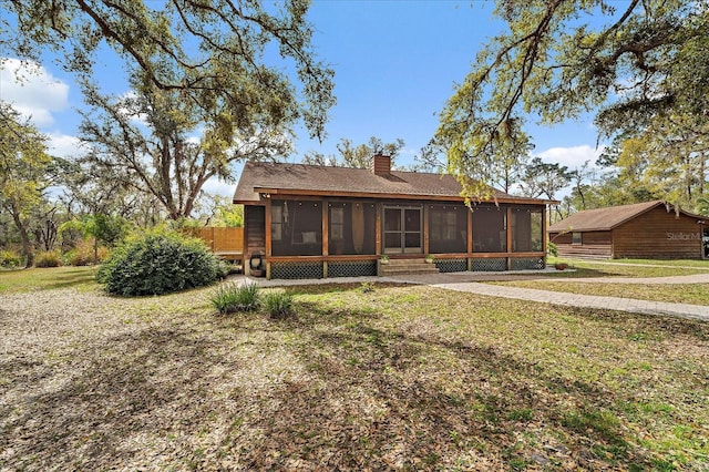 rear view of property with a yard, a sunroom, and a chimney