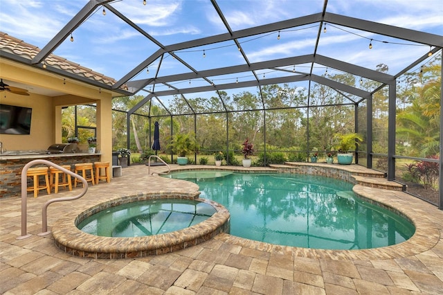 view of pool featuring outdoor dry bar, a pool with connected hot tub, a patio area, exterior kitchen, and a lanai