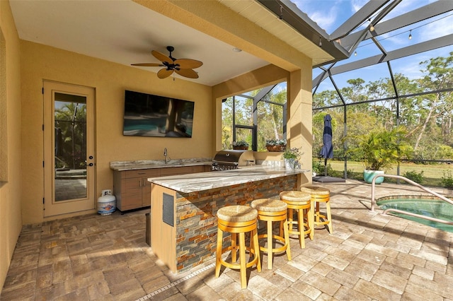 view of patio / terrace with glass enclosure, outdoor wet bar, exterior kitchen, and area for grilling