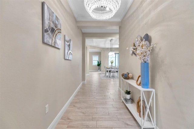 hallway featuring baseboards, a chandelier, crown molding, and wood finish floors