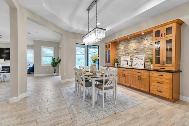 dining space featuring recessed lighting, baseboards, wood tiled floor, a tray ceiling, and a glass covered fireplace