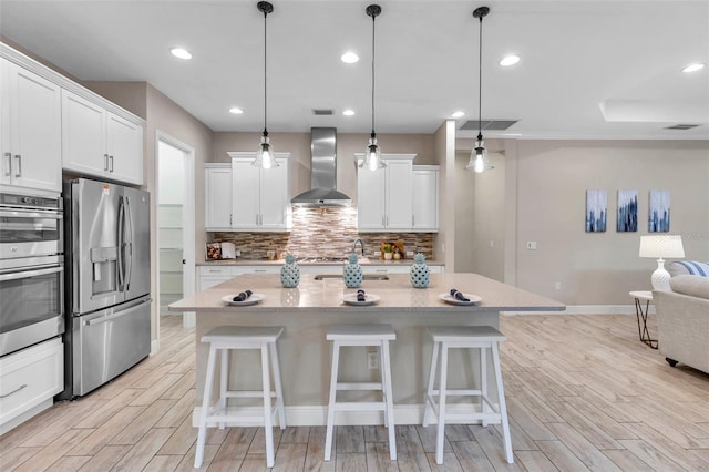 kitchen with a kitchen breakfast bar, appliances with stainless steel finishes, wall chimney range hood, wood tiled floor, and tasteful backsplash